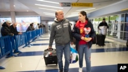 FILE - Mohammed Hafar, left, helps his daughter Jana with her luggage as they leave JFK Airport in New York, Dec. 3, 2019. 