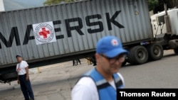 Volonteri stoje pored kamiona sa oznakom Međunarodne federacije društava crvenog krsta i crvenog polumeseca, koji je dovezao humanitarnu pomoć, u Karakasu, Venecuela, 31. jula 2019.