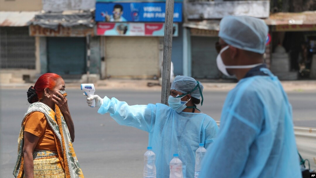 An Indian health worker checks the temperature of a woman during lockdown to prevent the spread of new coronavirus in Ahmedabad, India, Wednesday, April 8, 2020.