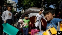 Children carry toys and bags leave from their family's tent at Victoria square, where hundreds migrants and refugees stay temporarily before trying to continue their trip to more prosperous northern European countries, in Athens, Oct. 1, 2015. 