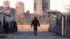 FILE - A township resident walks past Lonmin's Marikana platinum mine, June 13, 2014. 