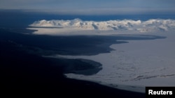 FILE - Pegunungan yang diselimuti salju dan Samudra Arktik di pantai Svalbard dekat Longyearbyen, Norwegia, 5 April 2023.