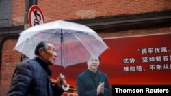 A man walks with an umbrella past a picture of Chinese President Xi Jinping on a street ahead of the National People's Congress (NPC), in Shanghai