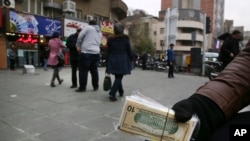 FILE - A street money exchanger holds Iranian and U.S. banknotes in downtown Tehran, Iran.
