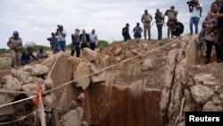 Pihak berwenang dan media lokal memeriksa poros tambang di Stilfontein, Afrika Selatan, pada 15 November 2024. Ratusan penambang ilegal diyakini bersembunyi di dalam porong tambang tersebut. (Foto: Reuters/Ihsan Haffejee)