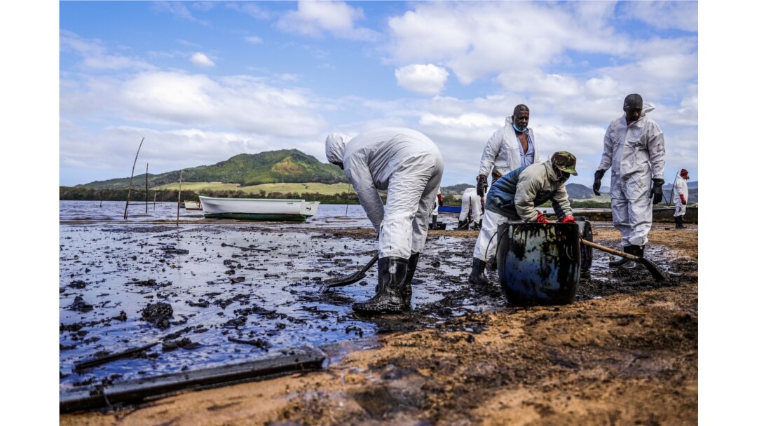 People scoop leaked oil from the vessel MV Wakashio, belonging to a Japanese company but Panamanian-flagged, that ran aground and caused oil leakage near Blue bay Marine Park in southeast Mauritius, Aug. 9, 2020.