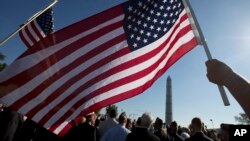 Anggota Marinir AS Terri Shreiner mengibarkan bendera AS dalam pawai di Washington Memorial, menuntut penghentian penutupan sebagian kegiatan pemerintah, di Washington, 15 Oktober 2013.
