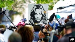 Potret Britney Spears terlihat dibawa oleh para pendukung dan anggota media di luar sidang pengadilan tentang konservatori penyanyi pop di Gedung Pengadilan Stanley Mosk, di Los Angeles, 23 Juni 2021. (Foto: AP)