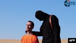 Seorang militan ISIS bersama pekerja bantuan Inggris David Haines (kiri) sebelum ia dibunuh di sebuah lokasi di Suriah (foto: dok).