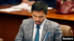 FILE - Philippine senator and boxing champion Manny Pacquiao reads his briefing materials as he prepares for the Senate session in Pasay city, Metro Manila, Philippines, Sept. 20, 2016. 