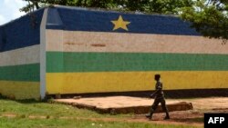FILE - A man walks in front of the jail of Bangui, "Maison Centrale de Ngaragba," whose walls are painted with the colors of the flag of Central African Republic, April 22, 2014. 