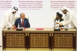 FILE - US peace envoy Zalmay Khalilzad, left, and Mullah Abdul Ghani Baradar, the Taliban group's top political leader, sign a peace agreement between Taliban and US officials in Doha, Qatar, Feb. 29, 2020.