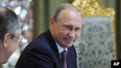 Russian President Vladimir Putin smiles as he listens to Russia's Foreign Minister Sergey Lavrov, left, at the meeting of the Collective Security Treaty Organization (CSTO) in Dushanbe, Tajikistan, Tuesday, Sept. 15, 2015.
