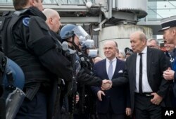 French Interior minister Bernard Cazeneuve , 2nd right, and Defence Minister Jean-Yves Le Drian shake hands with French police officers as they inspect security measures at Charles de Gaulle airport, in Roissy, north of Paris, March 23, 2016.