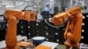 A Chinese worker is seen behind orange robot arms at Rapoo Technology factory in the southern Chinese industrial boomtown of Shenzhen, Aug. 21, 2015. Automation could wipe out two thirds of jobs in some countries, the World Bank warns.