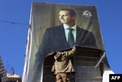Seorang militan antipemerintah merobek potret Presiden Suriah Bashar al-Assad di Aleppo, 30 November 2024, setelah jihadis dan sekutunya memasuki kota tersebut. (Foto: AFP)