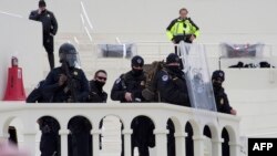 Polisi mengawasi massa pendukung Trump yang melakukan aksi protes di Gedung DPR AS, Capitol Hill di Washington, D.C., 6 Januari 2021. (Foto: Joseph Prezioso / AFP)