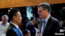 美国驻WTO大使习达难(右)在瑞士日内瓦举行的世界贸易组织（WTO）会议上与中国驻WTO大使张向晨交谈。（2018年7月26日）