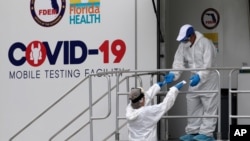 Health care workers work at a walk-up COVID-19 testing site during the coronavirus pandemic, Friday, July 17, 2020, in Miami Beach, Fla. The mobile testing truck is operated by Aardvark Mobile Health, which has partnered with the Florida Division of…