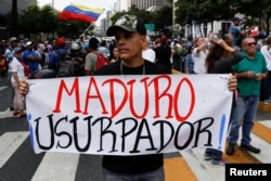 A man holding a placard that reads "Maduro usurper" takes part in a gathering with members of the Venezuelan National Assembly in Caracas, Venezuela, Jan. 11, 2019.