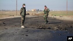Dua tentara Kurdi Irak menyelidiki lokasi serangan bom oleh ISIS yang diduga berasal dari senjata kimia di Irak utara (14/3).