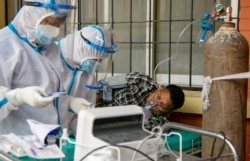 Nepalese paramedics treat a COVID-19 patient outside an emergency ward of a government run hospital in Kathmandu, Nepal, May 7, 2021.