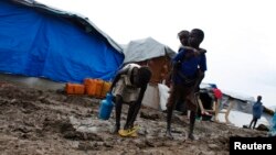 A boy carries a girl as they walk through the mud in an internally displaced persons (IDP) camp inside the U.N. base in Malakal, South Sudan, July 24, 2014. 