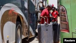 Sejumlah warga tampak berdiri di samping bus di saat rombongan yang bergerak meninggalkan Sudan tiba di Pelabuhan Argeen, Mesir, pada 28 April 2023. (Foto: Reuters/Mohamed Abd El Ghany)