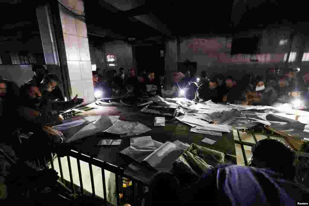 People search through papers as they join members of the Syrian civil defense group, known as the White Helmets, to search for prisoners underground at Sednaya prison, in Sednaya, after rebels seized the capital and announced that they have ousted President Bashar al-Assad.