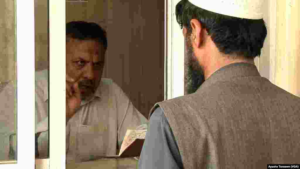 Pakistani immigration official checking an Afghan's passport at Torkham border crossing.