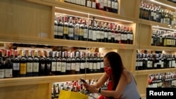 Seorang wanita mengenakan masker berada di luar sebuah toko minuman keras. Bangkok dan beberapa provinsi lainnya melarang penjualan alkohol selama 10 hari mulai 10 April. (Foto: Reuters)