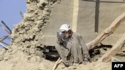 Penyintas di Dhall Bedi Peerander minum di rumahnya yang hancur akibat gempa 2013 di Pakistan. (Foto: Dok)