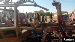 FILE - People walk past a destroyed vehicle following shelling by the Rapid Support Forces in Omdurman, Sudan, on Dec. 10, 2024. An attack on a hospital in Al-Fashir on Dec. 13 killed nine people, World Health Organization officials say. (Khartoum State Government via Reuters) 