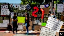 People stop to look at signs on a security fence at 16th and H Street, June 8, 2020, in Washington, after days of protests over the death of George Floyd, a black man who was in police custody in Minneapolis.