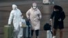 A passenger wearing a full-body protective suit catches the eyes of others as they walk out from the Beijing railway station in Beijing, Feb. 11, 2020. 