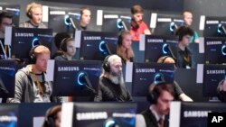 FILE - Visitors try out the latest video games at the Gamescom fair for computer games in Cologne, Germany, Aug. 22, 2017. Germany, a leader in digital advancement, could falter as Asia speeds ahead, according to a report published in Harvard Business Review.