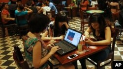 三名越南女孩在河内一家咖啡馆利用便携电脑和智能手机上网