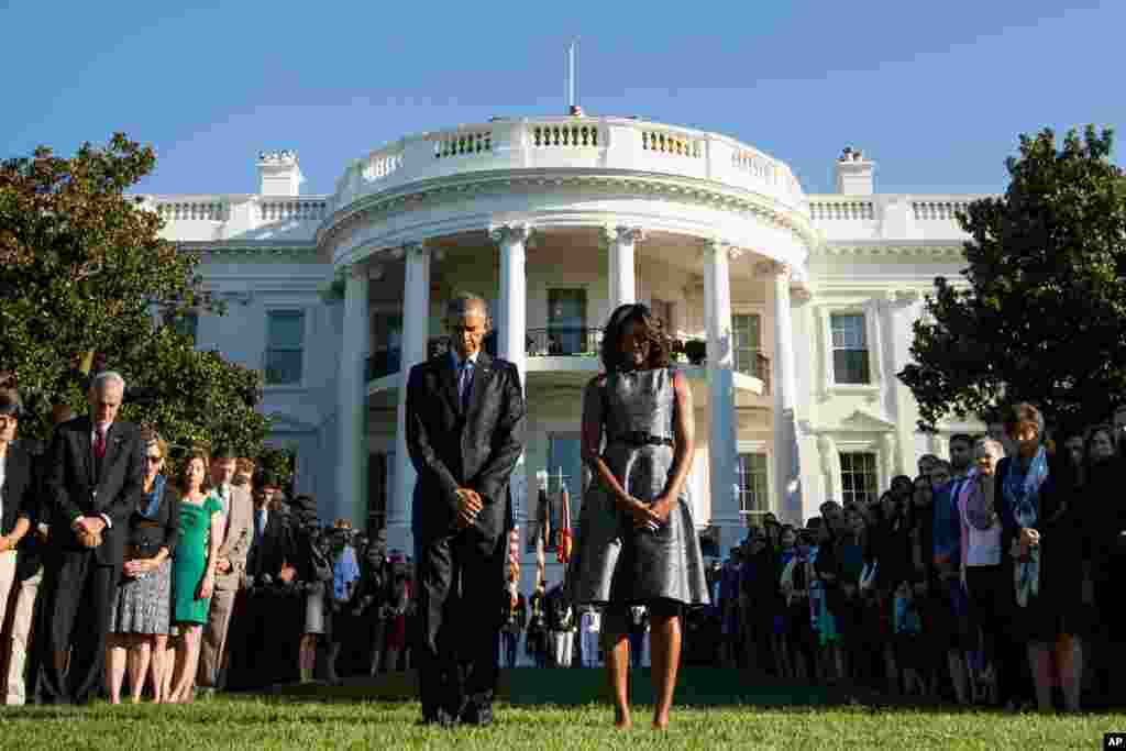 President Barack Obama, first lady Michelle Obama and others observe a moment of silence to mark the 14th anniversary of the 9/11 attacks, on the South Lawn of the White House in Washington, Sept. 11, 2015.