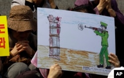 FILE - A North Korean defector reacts next to a drawing depicting a public execution of a North Korean soldier during a human rights rally in Seoul, South Korea, April 14, 2011.