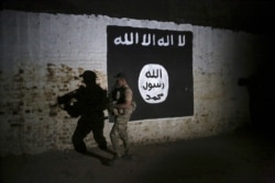 FILE - In this March 1, 2017 photo, an Iraqi soldier inspects a tunnel, adorned with an Islamic State group flag. According to the U.S. Treasury Department, the Islamic State has an estimated $100 million available in cash reserves.