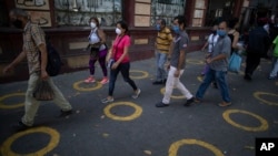 Yellow circles on a pavement serve as visual cues to help shoppers adhere to social distancing when lines form, as a precaution against the spread of the new coronavirus, near a popular market in Caracas, Venezuela, May 23, 2020.