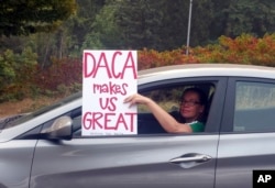 FILE - An unidentified woman holds a sign as she drives through rush-hour traffic in Portland, Ore., Sept. 5, 2017.