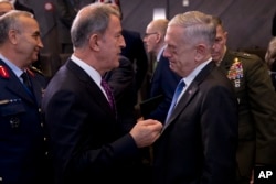 U.S. Secretary for Defence Jim Mattis, right, talks to Turkey's Defence Minister Hulusi Akar during the second day of a meeting of the North Atlantic Council at a gathering of NATO defence ministers at NATO headquarters in Brussels, Thursday, Oct. 4, 2018.