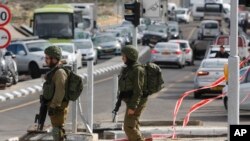Israeli soldiers stand at the scene of an attack near the settlement of Givat Assaf in the West Bank, Dec. 13, 2018. A Palestinian gunman opened fire at a bus stop outside a West Bank settlement Thursday, killing at least two Israelis before fleeing.