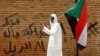 FILE - A protester makes a victory sign as he carries a Sudanese flag in front of the Defense Ministry in Khartoum, Sudan, April 19, 2019. 