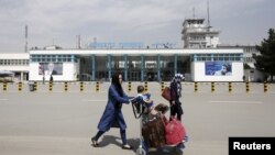 资料照片:阿富汗乘客从喀布尔的哈米德·卡尔扎伊国际机场前走过。(2016年3月29日) 
