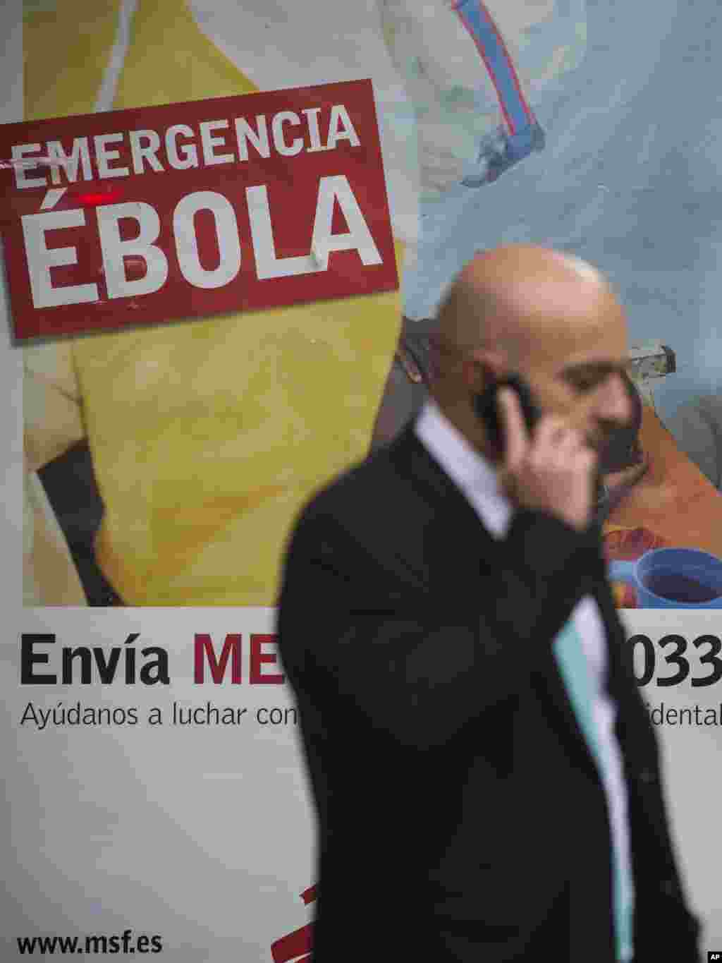 A man walks past a billboard that makes an appeal for financial help to fight Ebola in Africa, Madrid, Spain, Oct. 10, 2014.