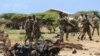 FILE - Jubaland forces walk near the site of an Aug. 22, car bomb attack near a military training base south of Mogadishu.