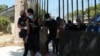 FILE - Plainclothes police officers escort four migrants who are detained as suspects for a fire that burned the Moria camp for refugees and migrants, on the island of Lesbos, Greece, Sept. 16, 2020. 