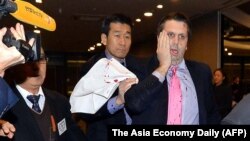 美国驻韩国大使李柏特(右)用手按住脸部刀伤离开世宗文化会馆